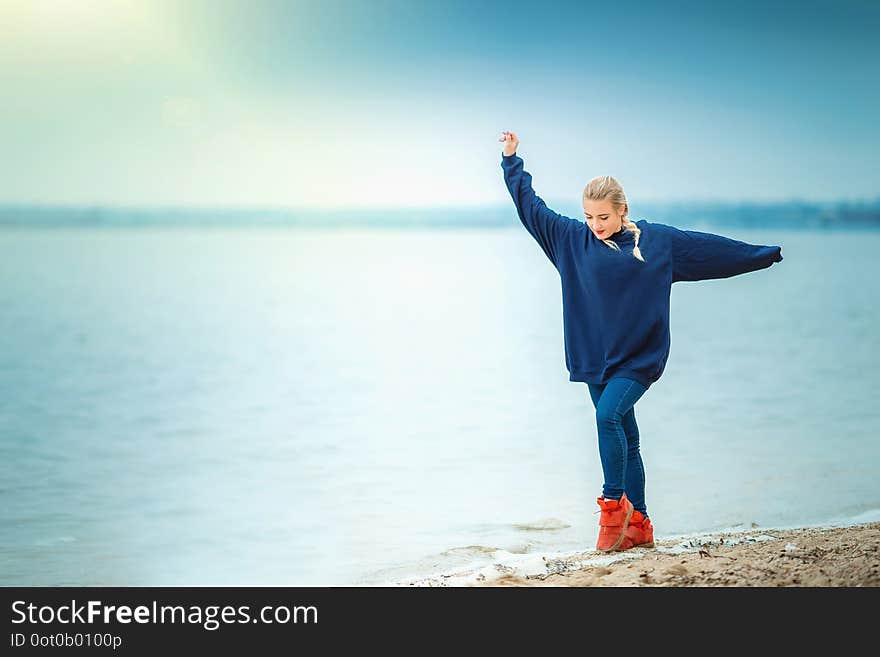 Girl dancing on the river beach in spring or autumn