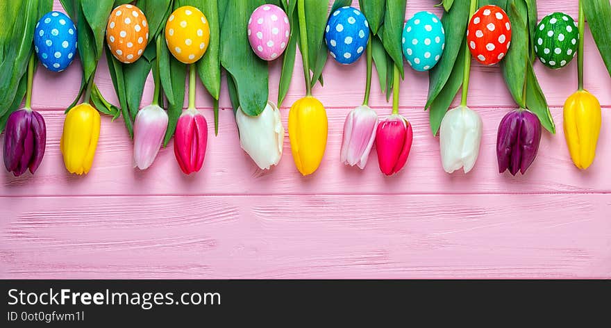 Easter eggs with colorful tulips on wooden background, easter holiday concept.