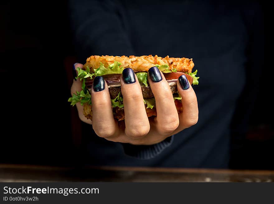 Healthy lifestyle, proper nutrition. Healthy rice burger with vegetables, herbs and cutlet in female hands. Horizontal frame