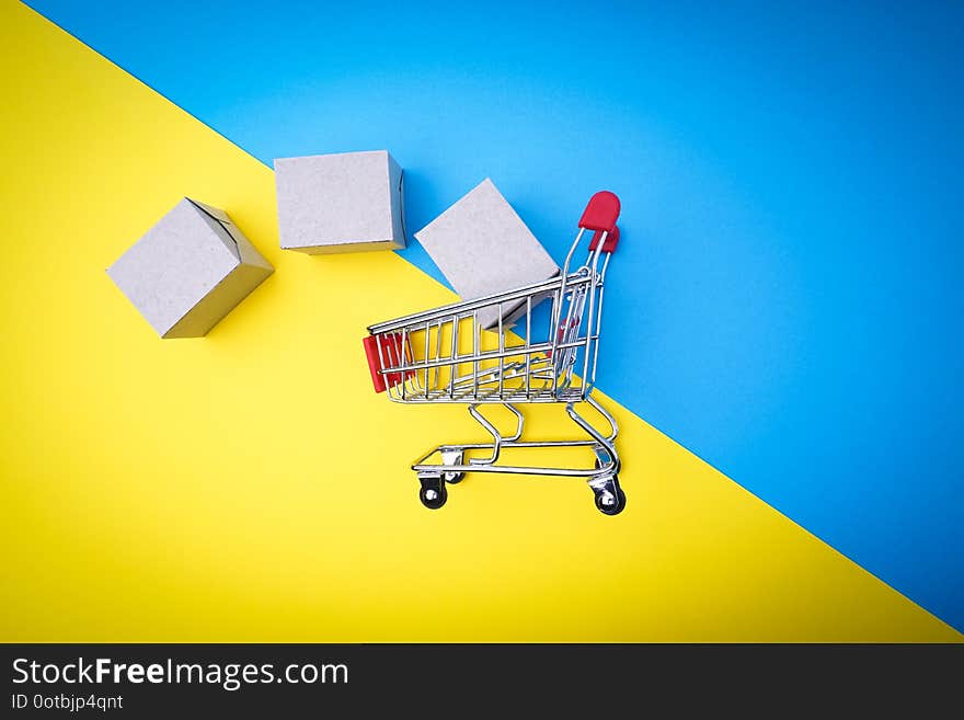 Shopping cart and box on blue and yellow background, business and shopping concept. Selective focus