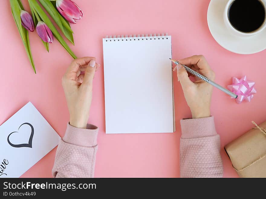 Styled feminine flatlay with pink tulip flowers, notebook, cup of coffee. copy space for text.