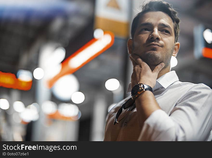 Young attractive businessman waiting for train in metro or subway on modern stylish platform. Close up. Man is late and nervous