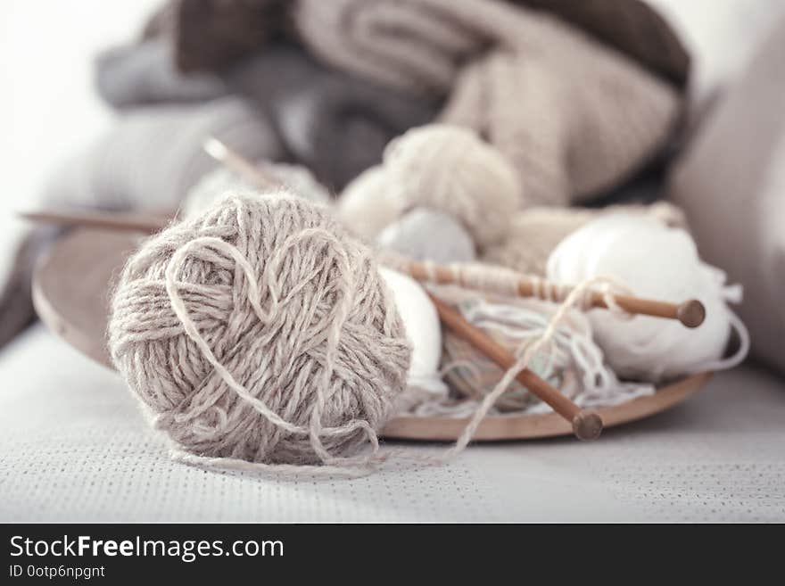 Vintage wooden spokes and threads for knitting in the shape of a heart on a wooden plate. Still life photo