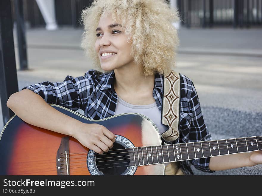 Cheerful girl playing the guitar the street