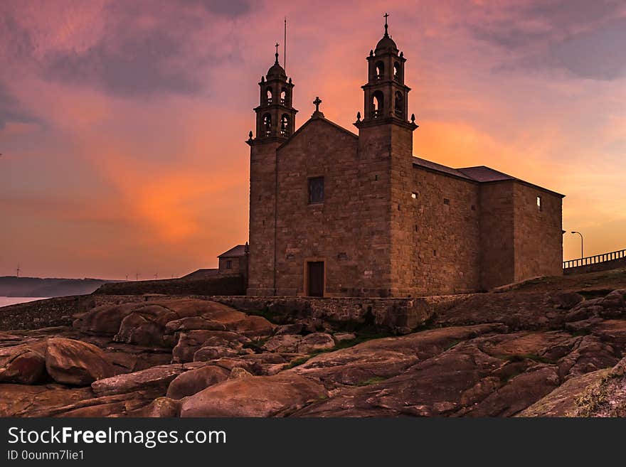 The Church of Virgen de la Barca, Muxia, Galicia, Spain shot at sunset, lots of orange and purples in the sky from a low angle