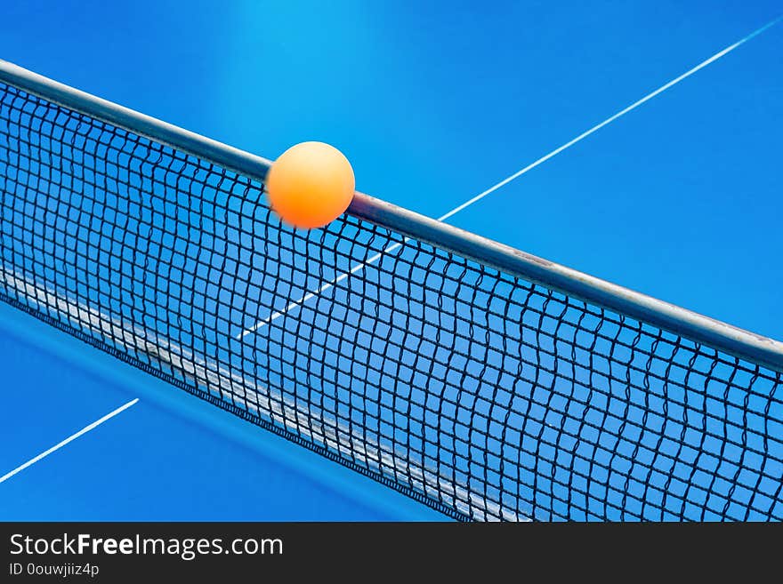 Yellow ball hits the netting on a blue pingpong table