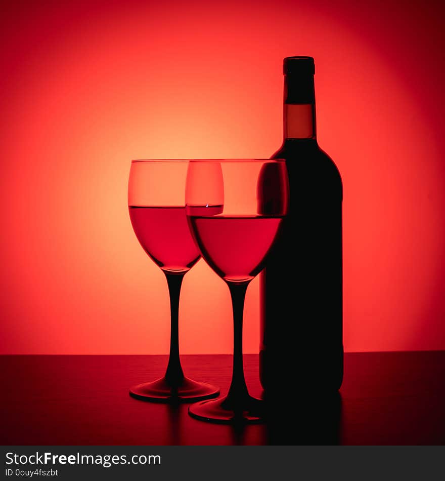 Wine glasses and bottle on red background