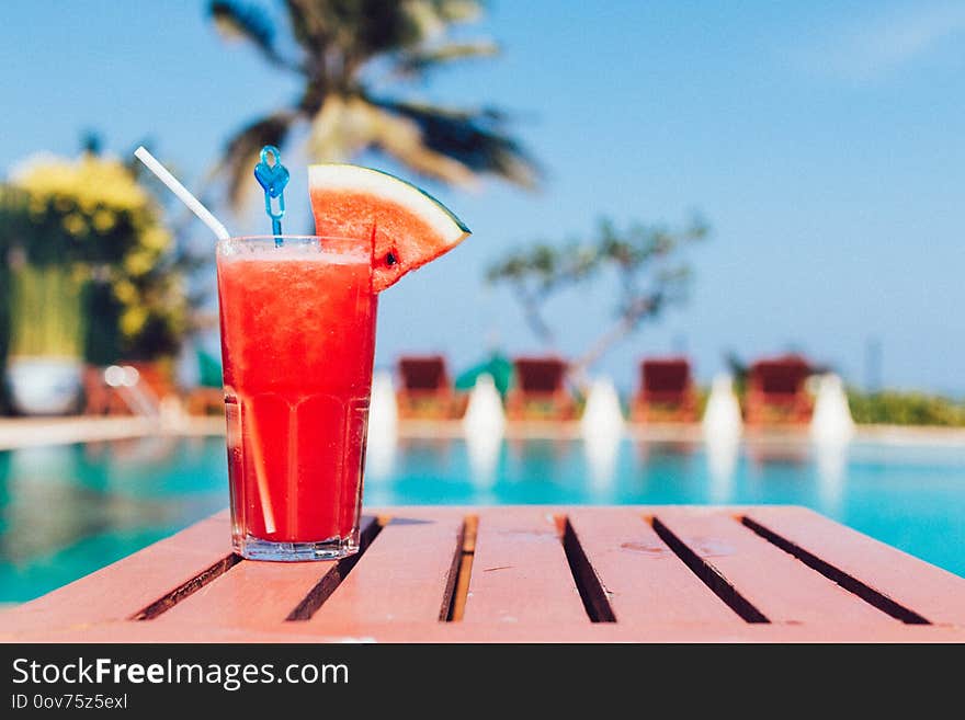 Healthy concept, Water melon smoothie on a wood table with swimming pool and blue sky background.