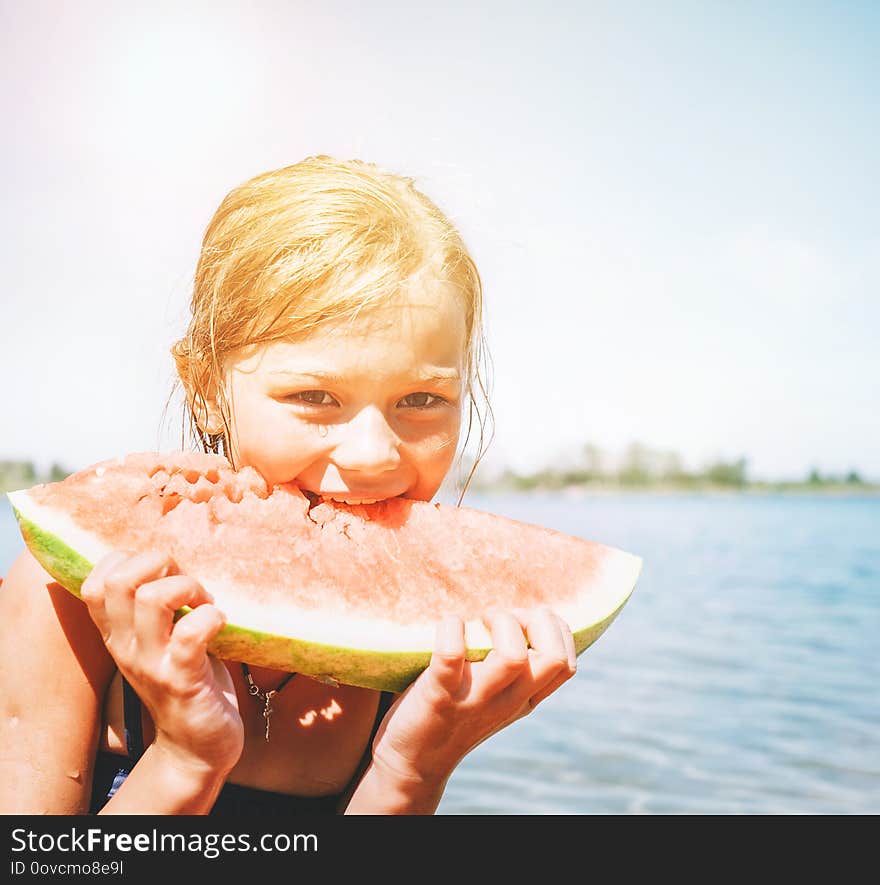 Little smiling Girl eating red watermelon portrait on the beach