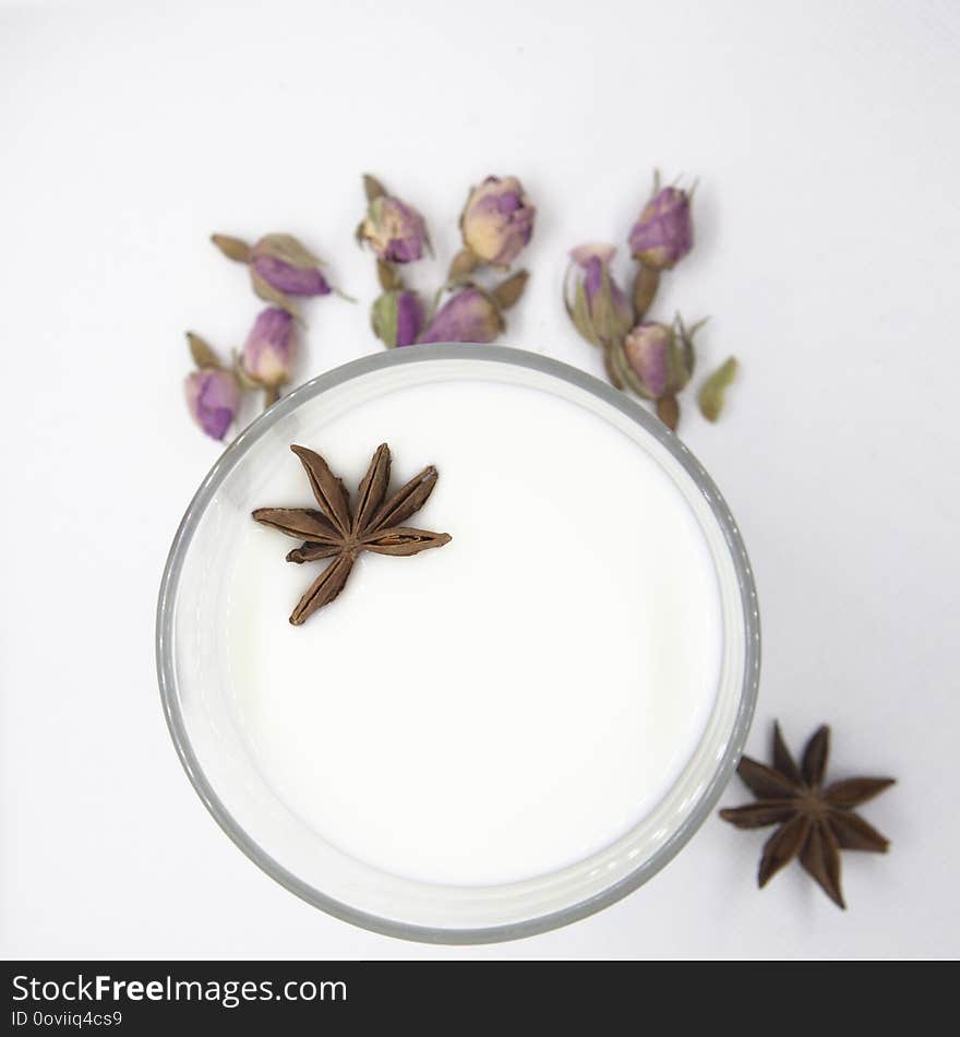 Still life with glass of milk, star anise and rose buds