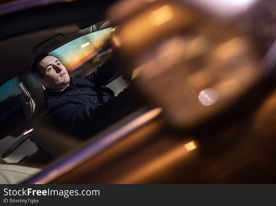 Handsome young man driving his car at night color toned image