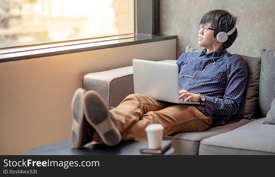 Asian man sitting on sofa looking out of window