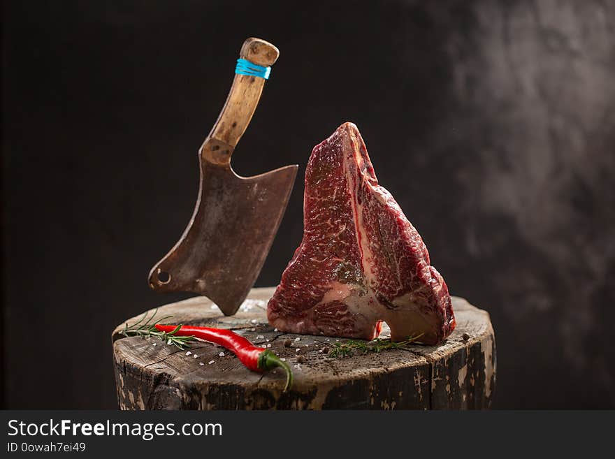 Raw Fresh Marbled Meat Beef ax on a stump on black background