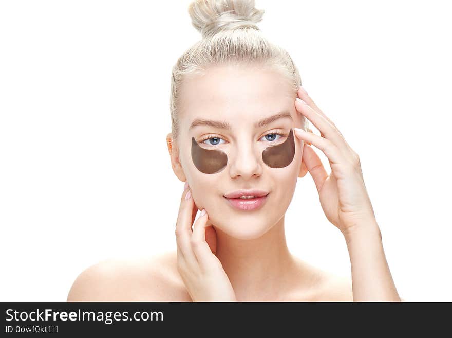 A beautiful young blond woman with eye patches and an expression of delight touches her face on a white background in isolation. C