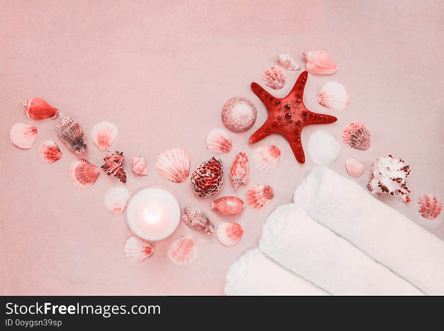 Red starfish and mollusk shells on pure white fine beach sand. Burning candle and three rolls of clean spa salon bath towels.Sea relax background with place for text, copy space. Top view, copy space. Red starfish and mollusk shells on pure white fine beach sand. Burning candle and three rolls of clean spa salon bath towels.Sea relax background with place for text, copy space. Top view, copy space