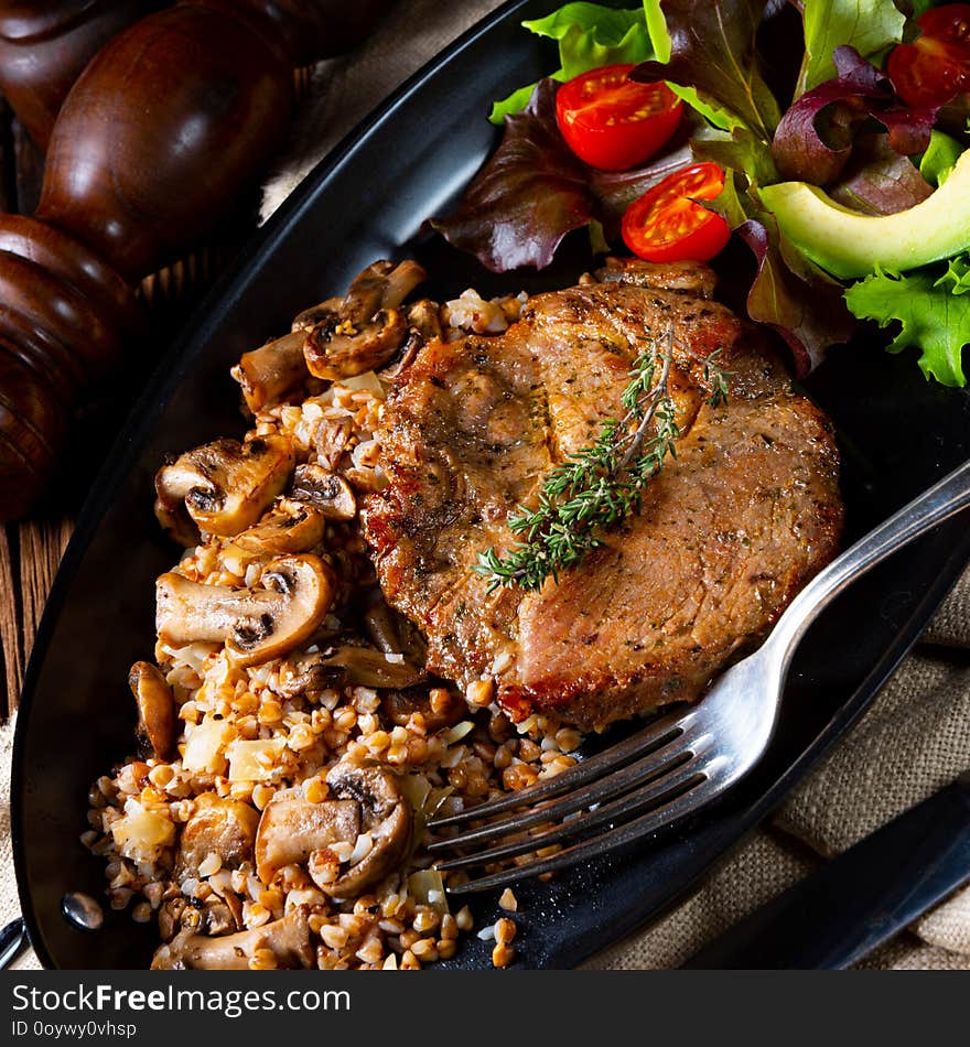 A Pork steak with mushrooms and buckwheat groats and mango salad