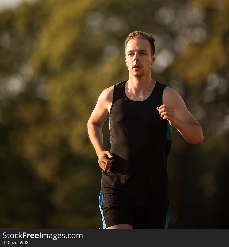 Handsome youg runner jogging outdoors on a lovely summer evening