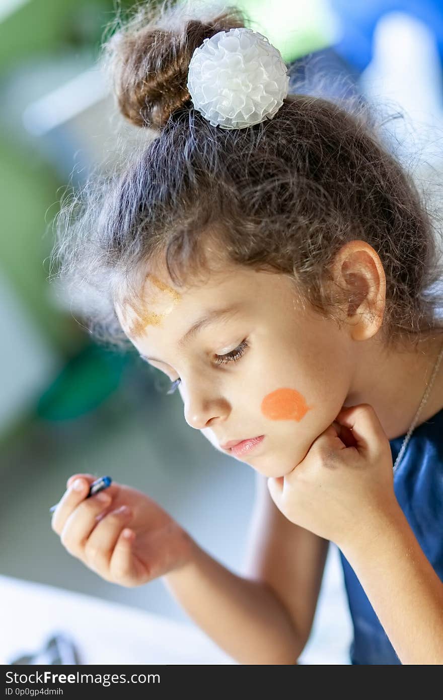 Girl draws on her face with special pencils for face painting