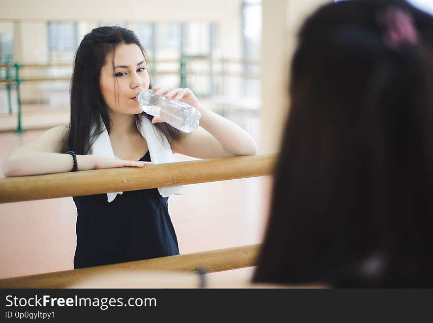 Young healthy woman drinking water in fitness