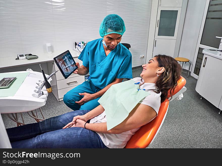 African male dentist explaining x-ray to the patient sitting in the chair