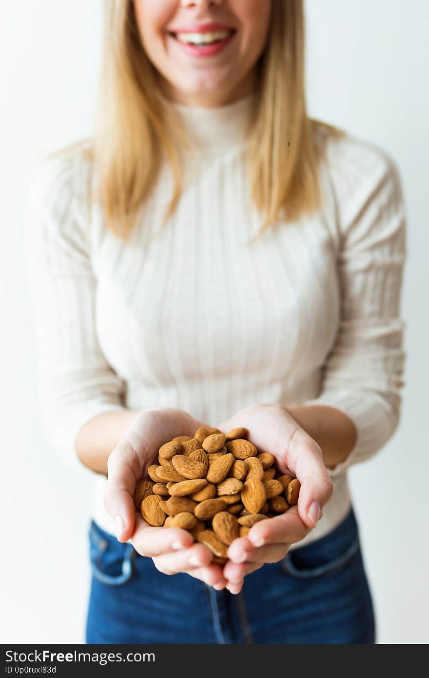 Shot of cheerful young woman hands holding almonds nuts on white background