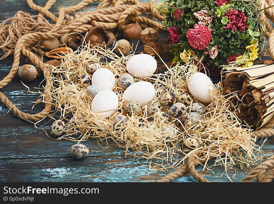 White chicken eggs and quail eggs near dry flowers. Eggs For Easter.