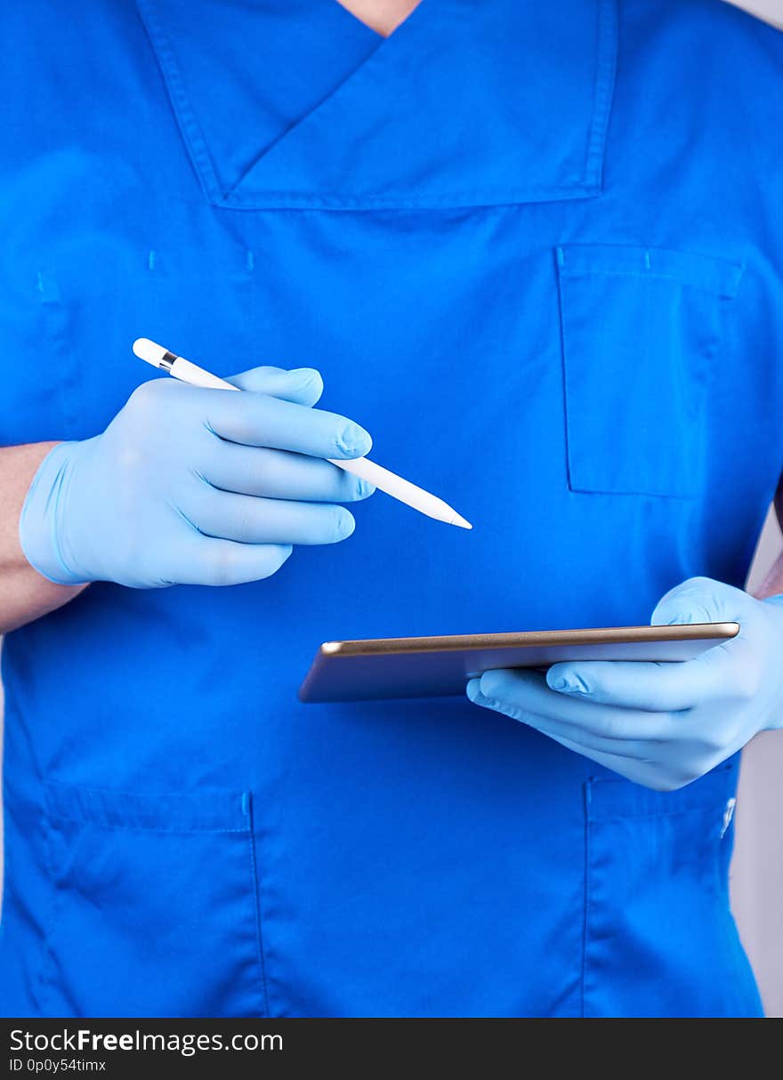 Doctor in blue uniform and latex gloves holding an electronic tablet and pencil, remote counseling