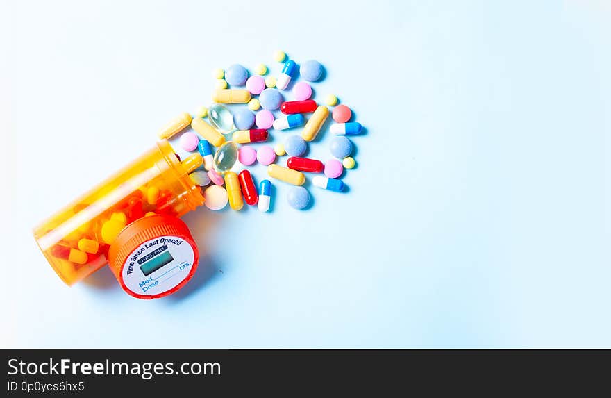 Pile of medical pills falling from bottle on blue background banner with copy space. Pile of medical pills falling from bottle on blue background banner with copy space