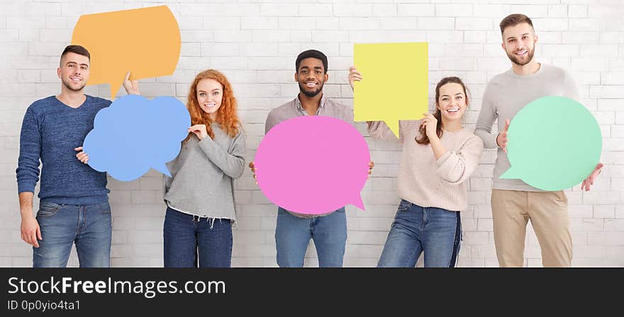 Friends holding empty speech bubbles over white brick wall, crop. Friends holding empty speech bubbles over white brick wall, crop