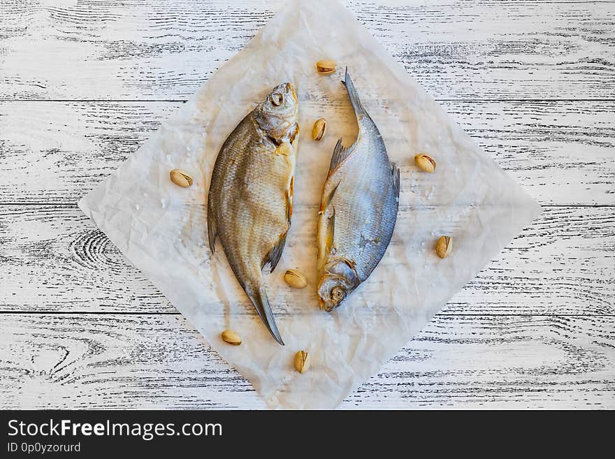 Two dried fish bream lie on a light wooden table