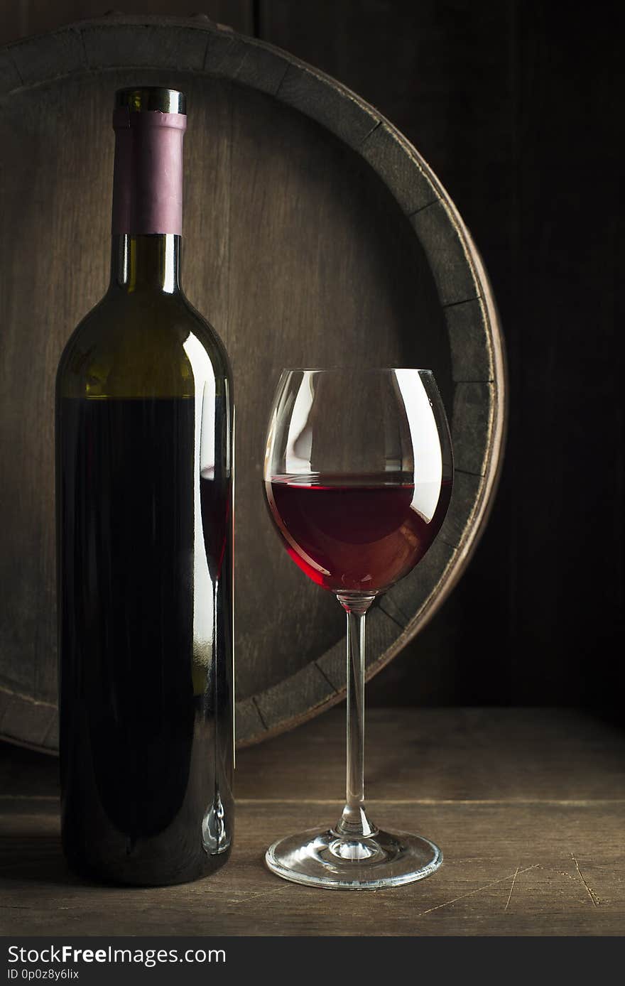 Glass and bottle of red wine on wooden background. Wine background. Glass and bottle of red wine on wooden background. Wine background