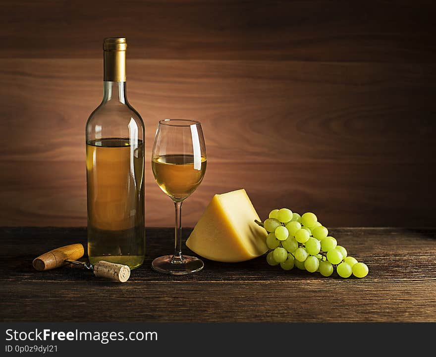 Bottle of white wine with snack food on old board. Glass of wine and cork with wooden background. Bottle of white wine with snack food on old board. Glass of wine and cork with wooden background