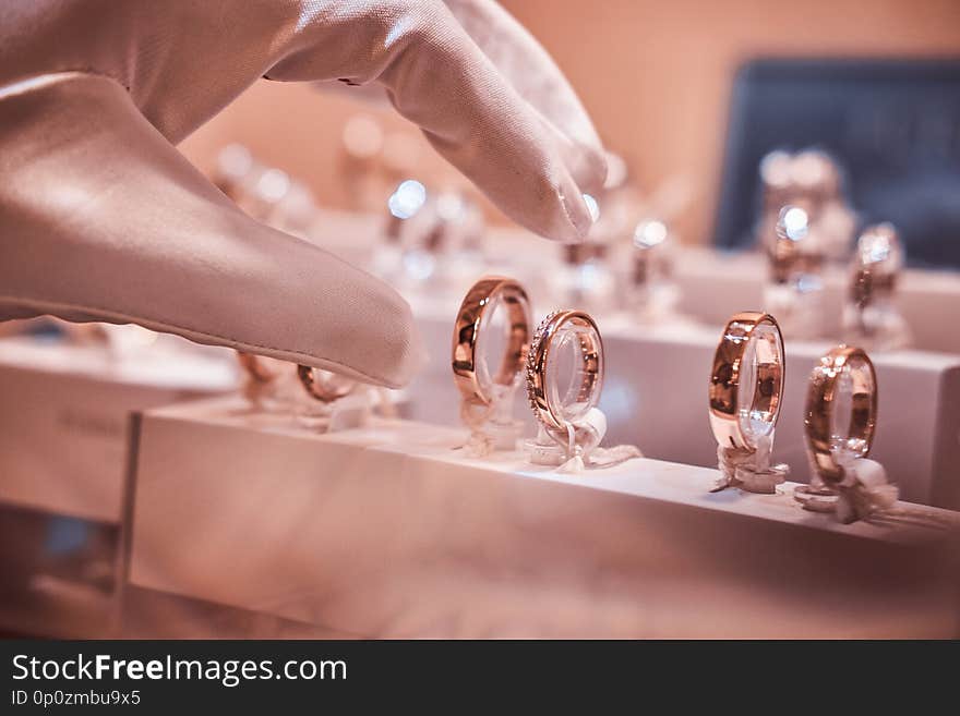 Hand in gloves takes to exclusive rings on the showcase of a jewelry store