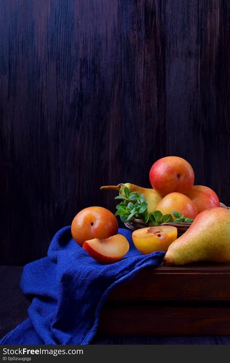 Red and yellow plums, pears and mint on a wooden table. Still life with copy space
