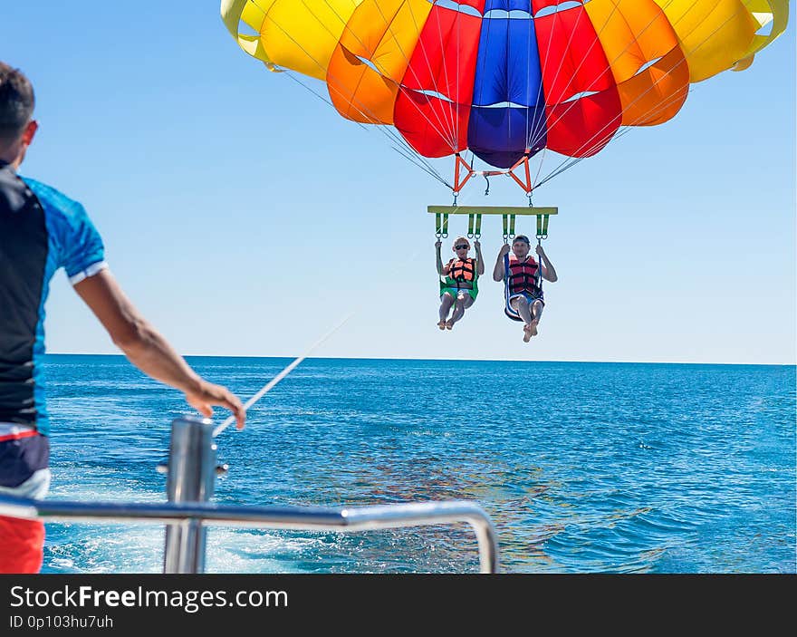 Happy couple Parasailing on Miami Beach in summer. Couple under parachute hanging mid air. Having fun. Tropical Paradise. Positive human emotions, feelings, family, travel, vacation