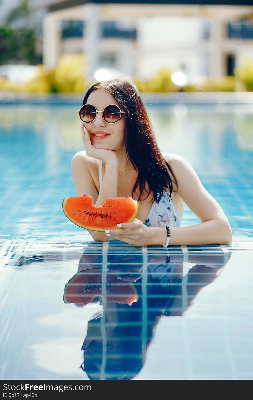 Brunette girl eating fruit by the pool