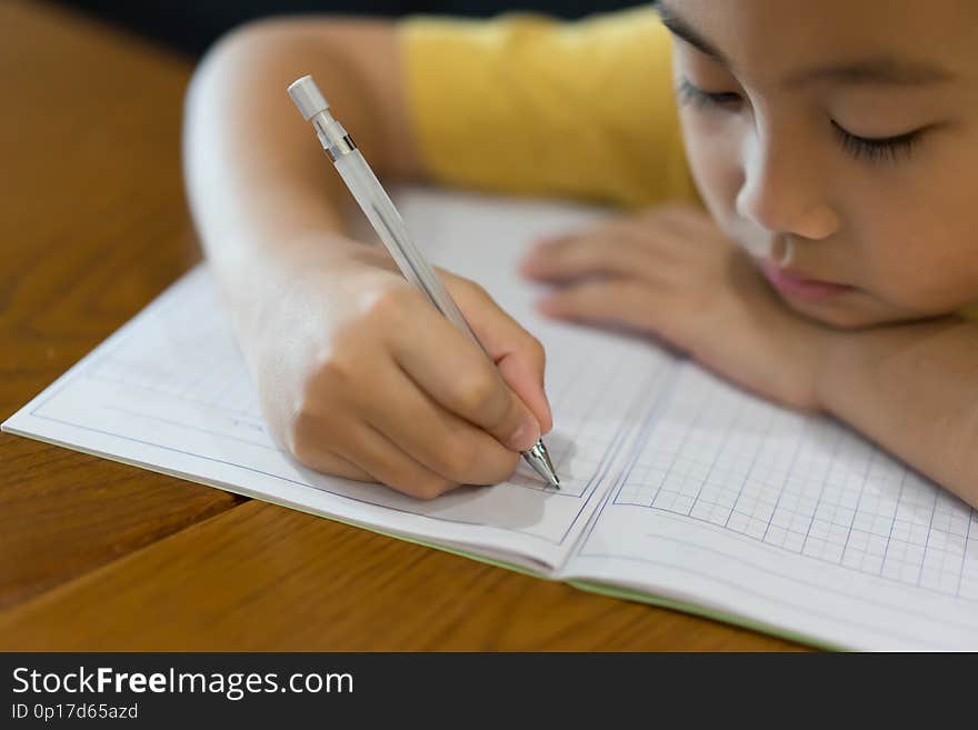 Little boy hand is writing homework at home.