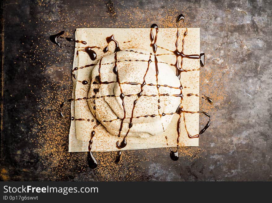 Chocolate meringue dessert decorated with glaze and chocolate powder. Selective focus.