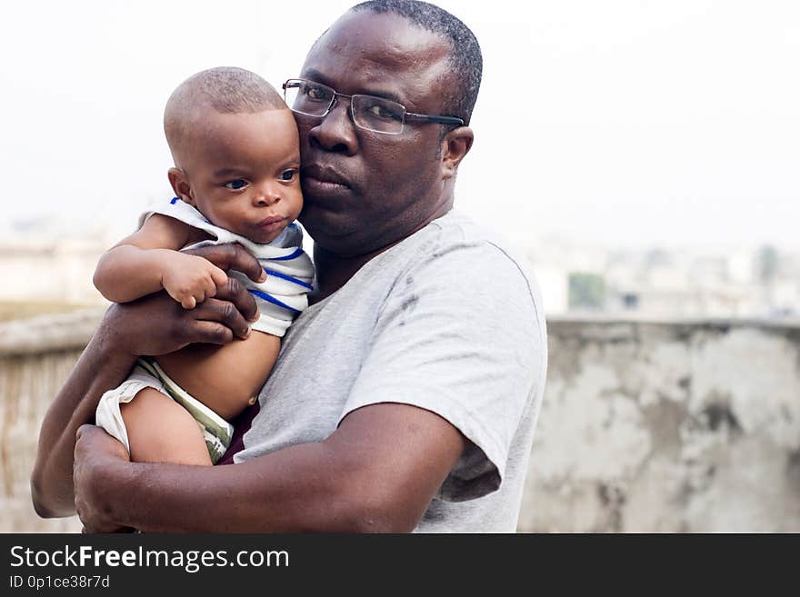 Middle aged men takes a picture with his baby while looking at the camera. Middle aged men takes a picture with his baby while looking at the camera