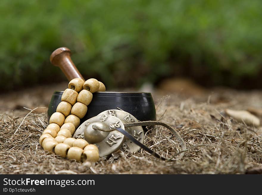 Tibetan singing bowl, mala beads and tibetan cymbals sitting in some hay. Tibetan singing bowl, mala beads and tibetan cymbals sitting in some hay