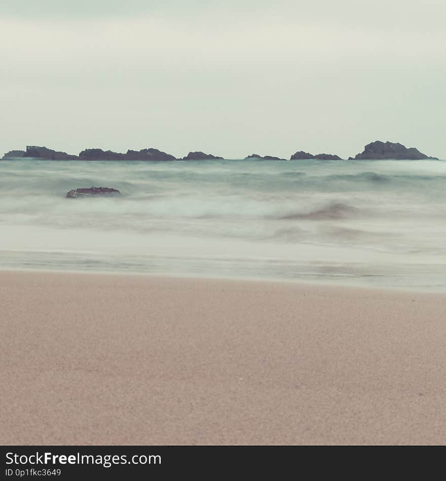 Fine art ocean waves and rocks landscape in pastel tones. vintage colors. beach, waves and sky in same tones for artistic outdoor conceptual image