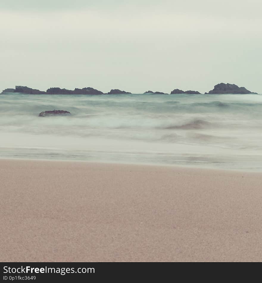 Fine art ocean waves and rocks landscape in pastel tones. vintage colors. beach, waves and sky in same tones for artistic outdoor