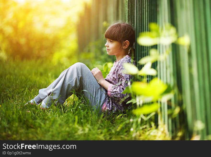 Little girl sitting on the grass in summer