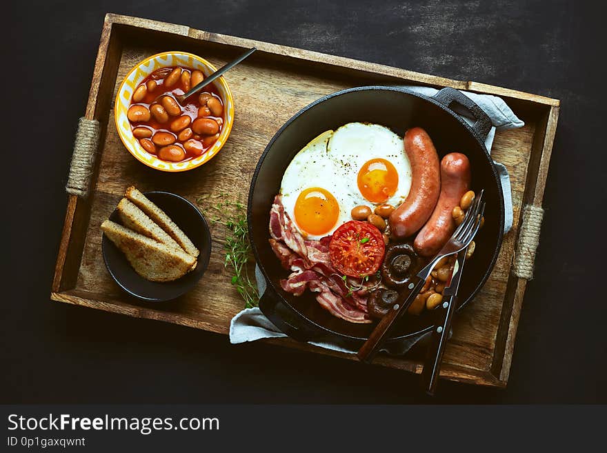Traditional English breakfast in a cast iron pan, view from above on rustic style table setting. Traditional English breakfast in a cast iron pan, view from above on rustic style table setting