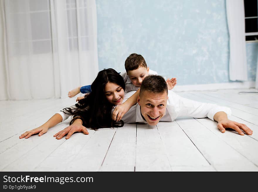 Young father have fun with daughter and son. Young family with children in white clothes.