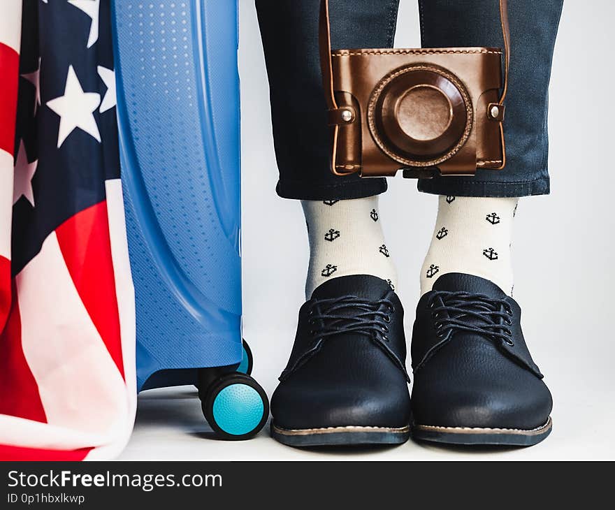 Stylish, beautiful suitcase, US Flag, men`s legs, bright socks with a nautical theme and shoes on a white, background. Close-up. Concept of style, fashion, beauty and travel. Stylish, beautiful suitcase, US Flag, men`s legs, bright socks with a nautical theme and shoes on a white, background. Close-up. Concept of style, fashion, beauty and travel