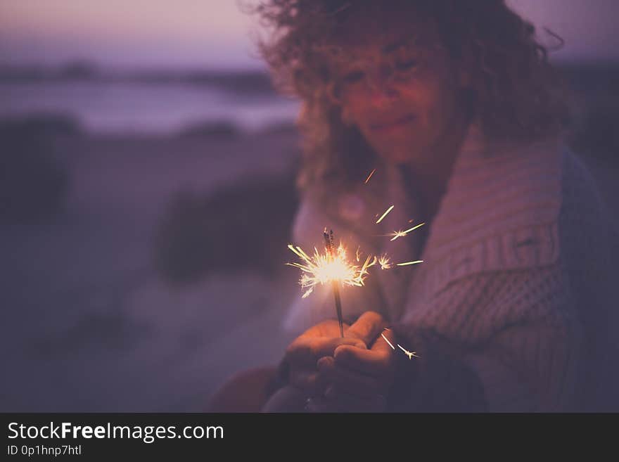 Single attractive woman defocused portrait taking alone sparkles light fireworks to celebrate new year or party event outdoor in alternative way with no friends around - sad and happy concept