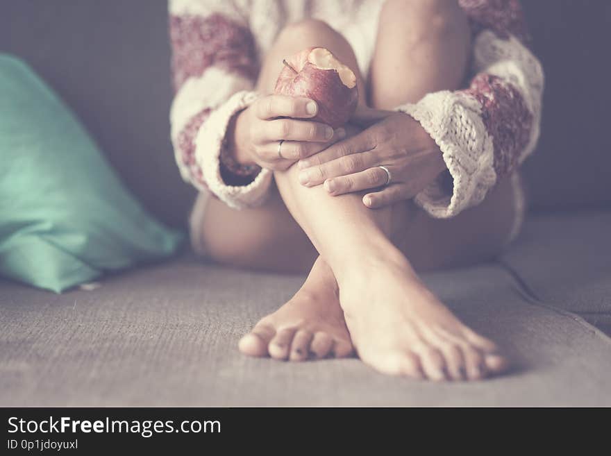 Vintage relaxed and peaceful colors and tone for body of woman sitting on the sofa eating an apple. focus on the fruit and