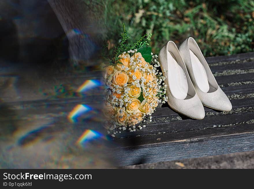 Wedding bouquet rings and shoes of the bride in the sun.