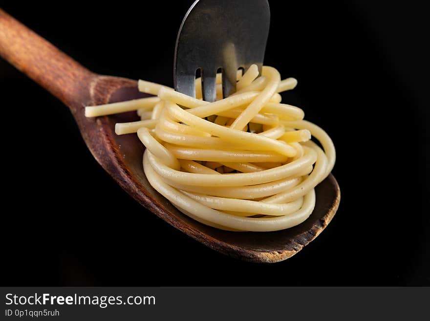 Tasty pasta on the tip of a fork. A tasty meal ready to be eaten. Dark background